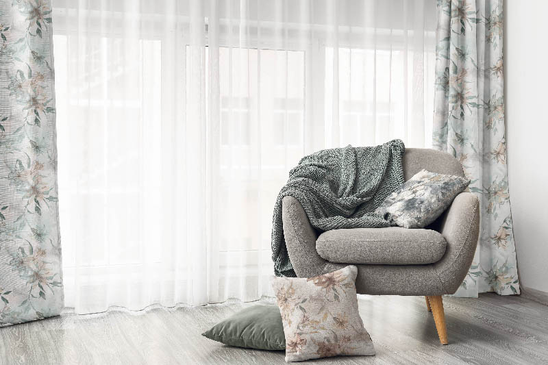 Comfortable armchair near light curtains in room